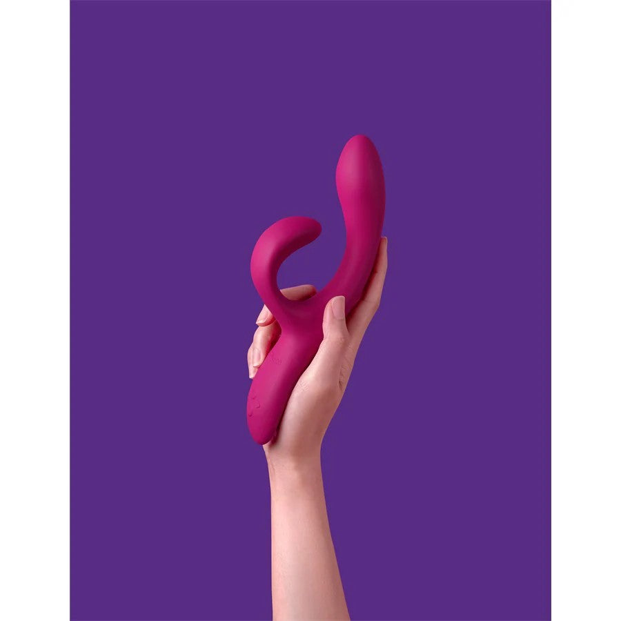Nova Rabbit Vibrator held upright in hand, highlighting dual stimulation tips and curved shape on purple backdrop
